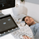 lady lying down looking up at an ultrasound machine whilst she has her babys gender determined