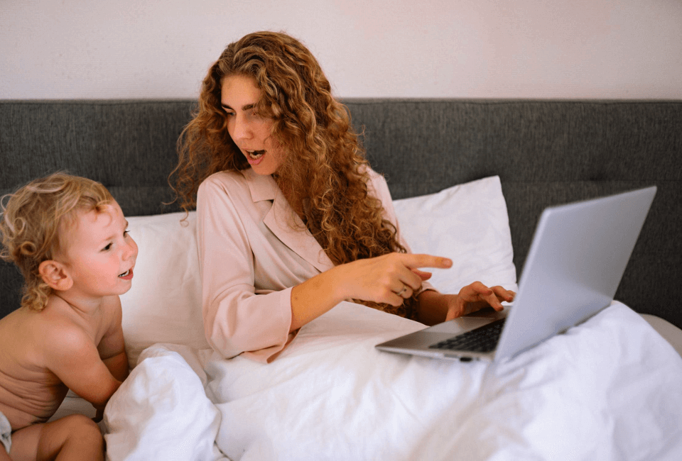 A lady sitting in bed pointing at her laptop and referring to gender prediction methods available online