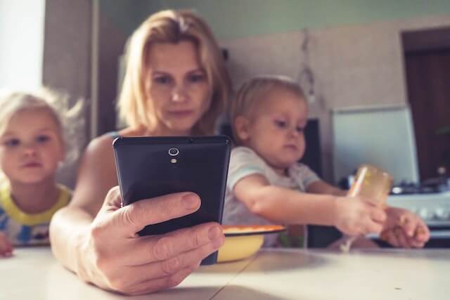 mother working from her mobile phone with a two kids either side of her